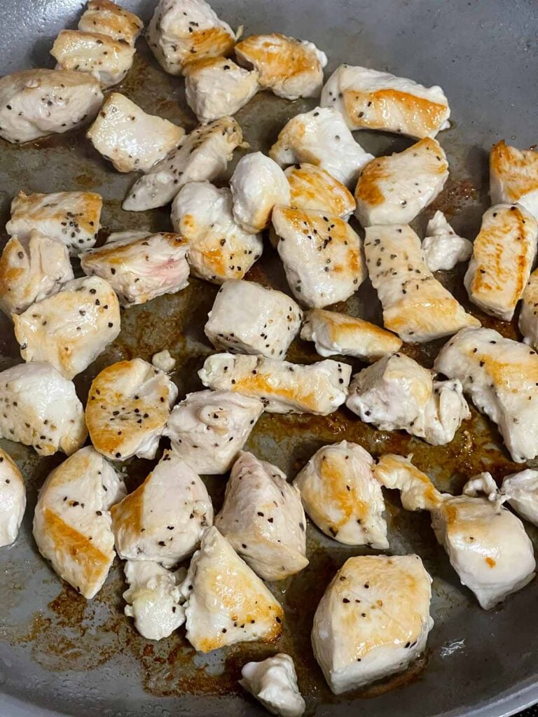 Cooked cubed chicken breast in a skillet.