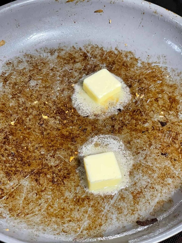 Butter melting in a skillet with fond.