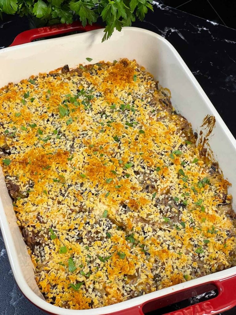 A cooked chicken and wild rice casserole in a staub baking dish.