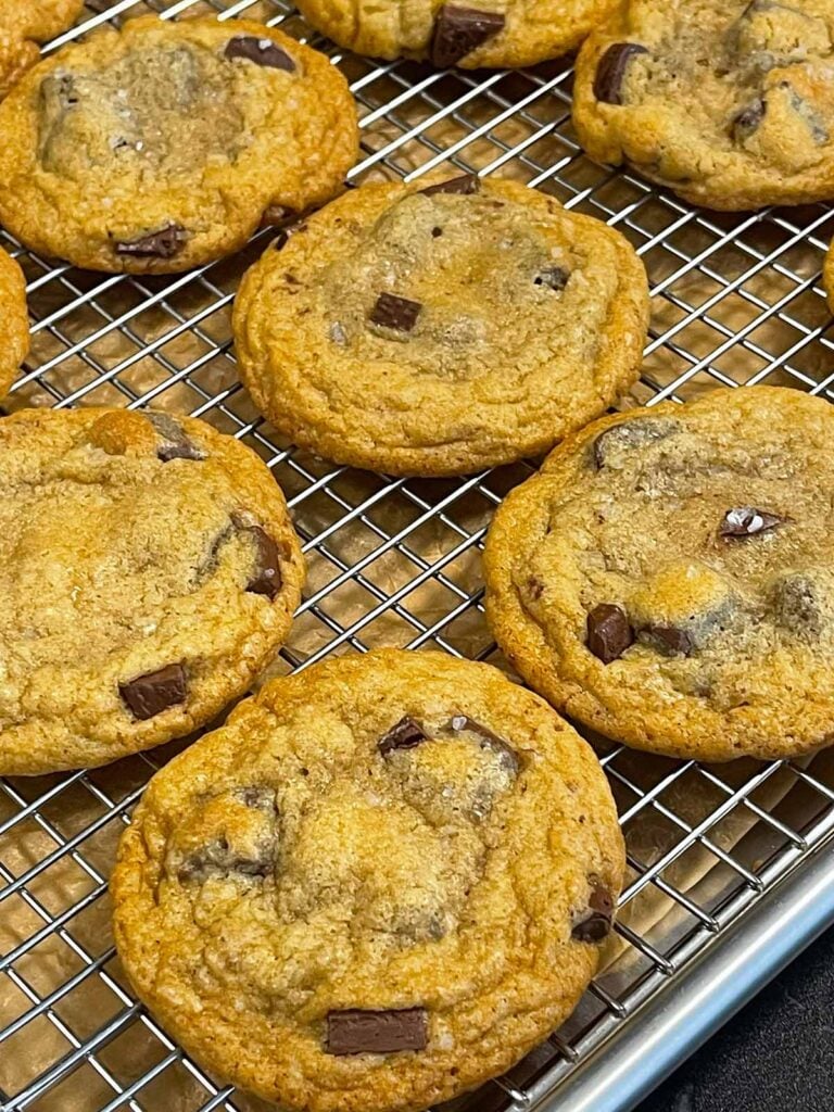 Baked crispy and chewy chocolate chip cookies on wire rack over a baking sheet.