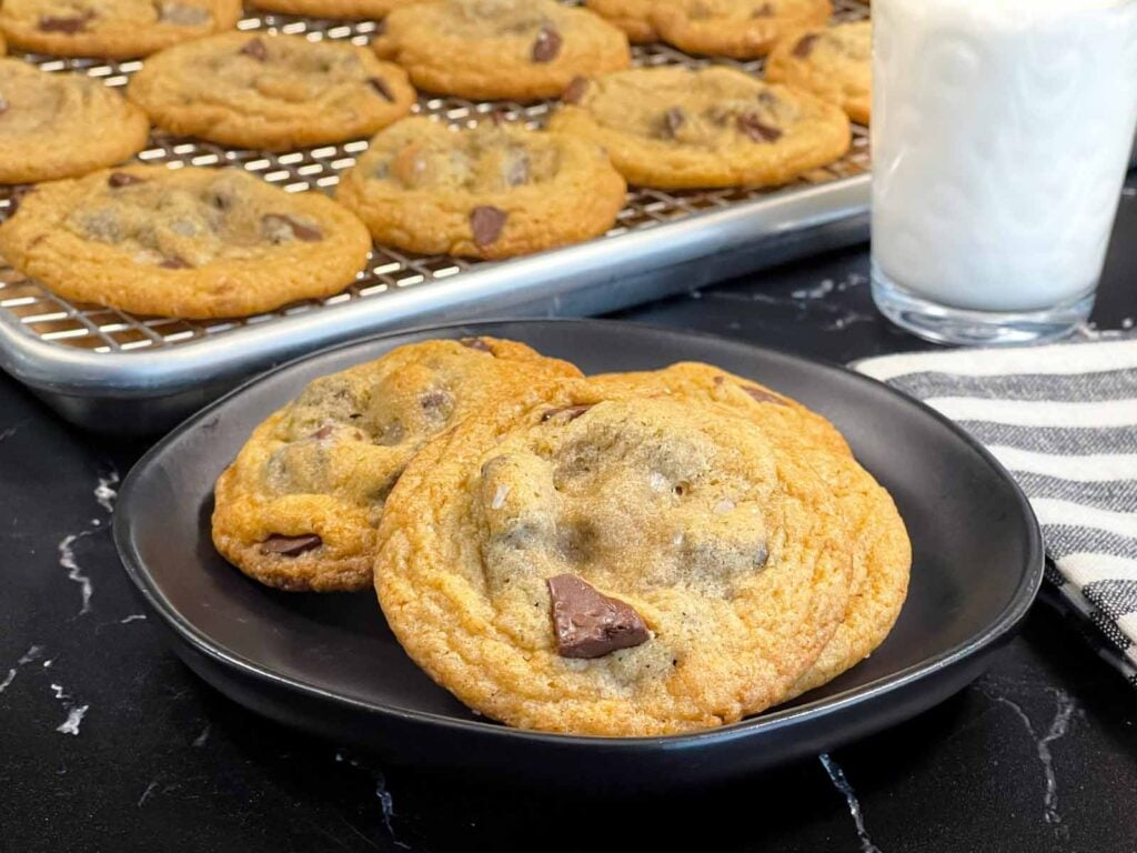 Crispy and chewy chocolate chip cookies on dark plate.