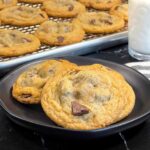 Crispy and chewy chocolate chip cookies on dark plate.