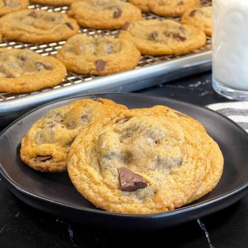 Crispy and chewy chocolate chip cookies on dark plate.