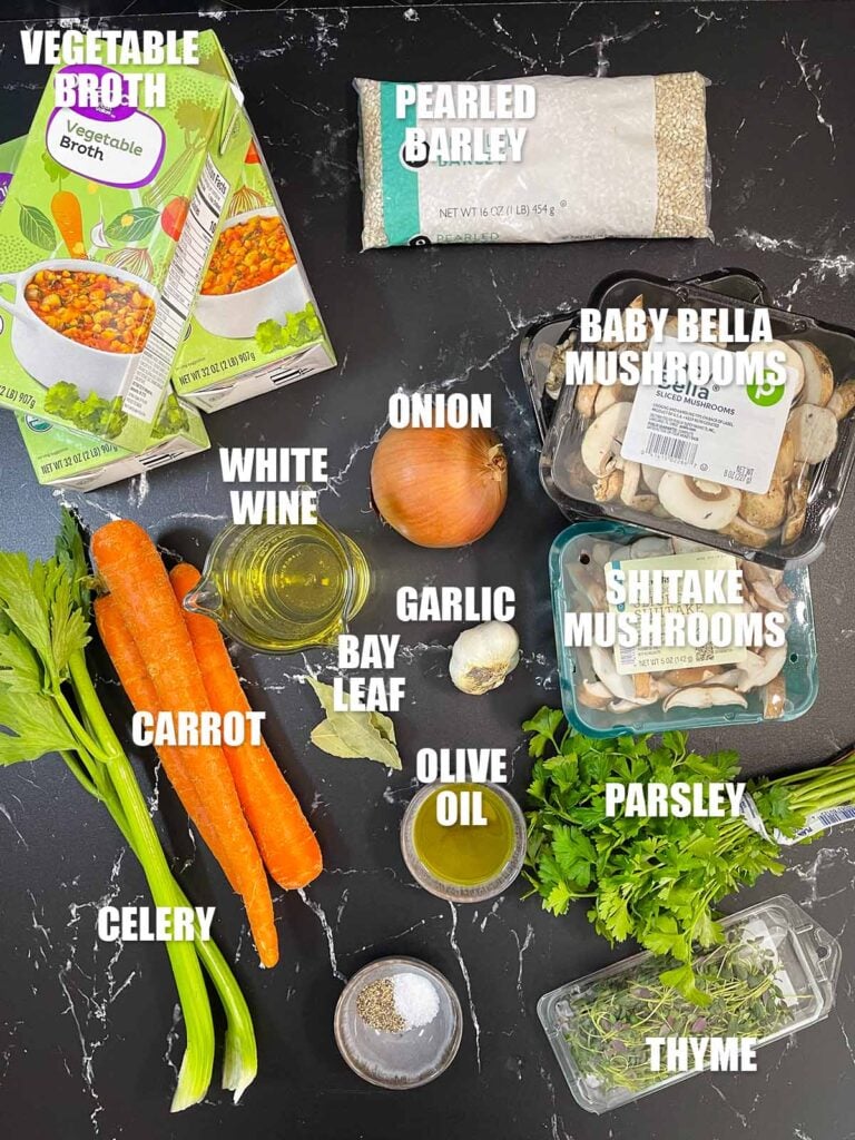 Mushroom barley soup recipe ingredients on a dark surface.