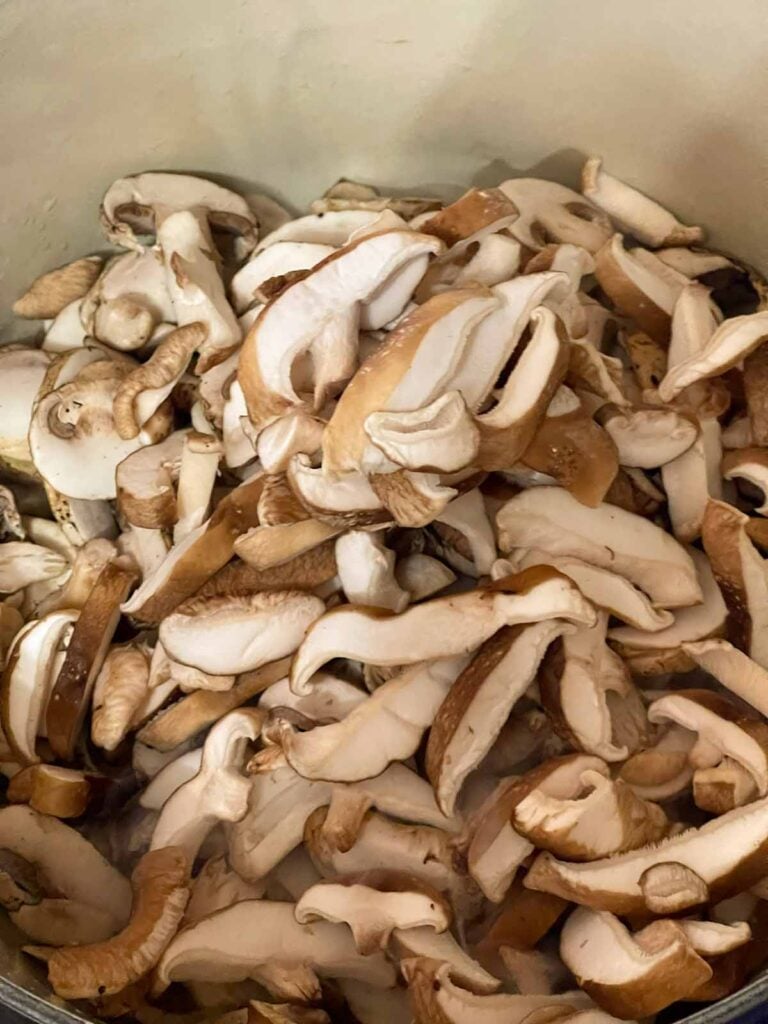 Raw mushrooms added to a Dutch oven for the mushroom barley soup recipe.