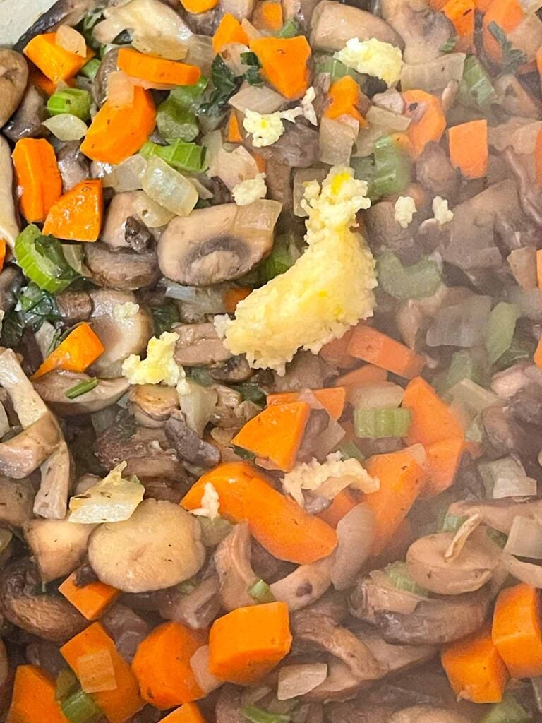 Minced garlic added to the vegetables in the Dutch oven for the mushroom barley soup recipe.