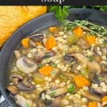 Mushroom barley soup in a dark bowl garnished with minced parsley and fresh thyme.