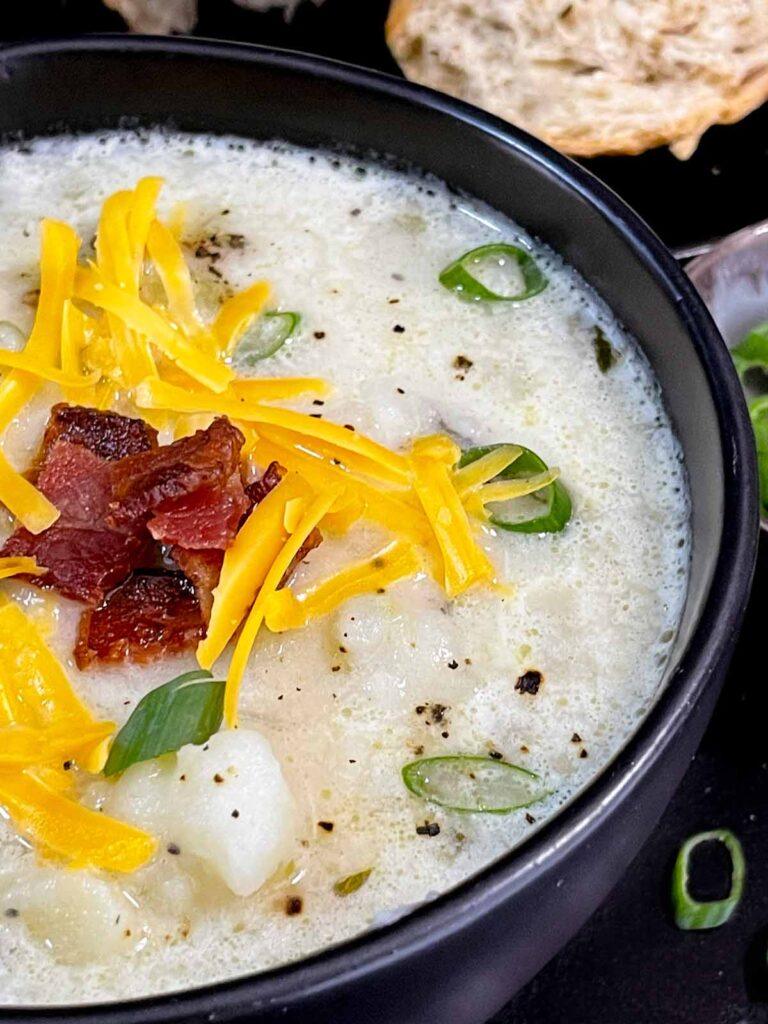 Creamy potato soup garnished in a dark bowl.