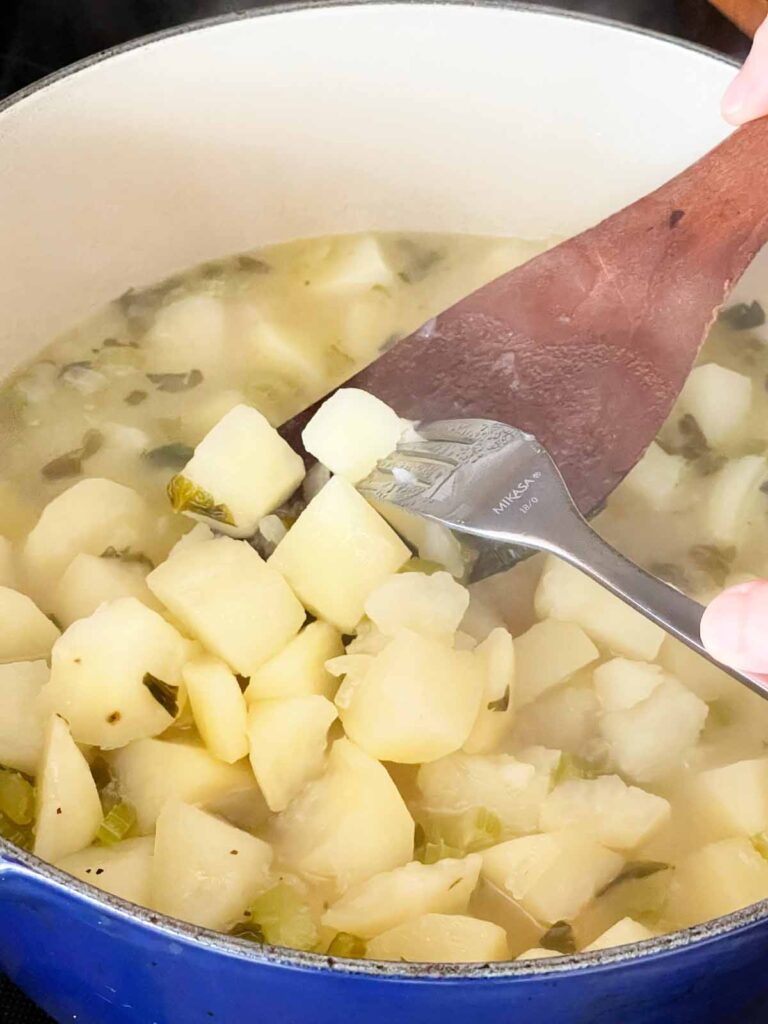 Fork testing the cooked potatoes for the potato soup.