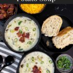 Creamy potato soup topped with diced bacon, shredded cheddar cheese, and diced green onions in dark bowls.