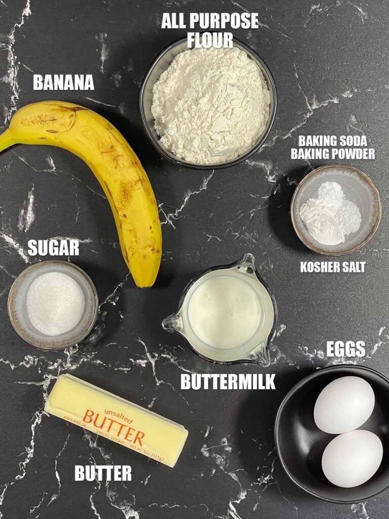 Ingredients for banana pancakes recipe including ripe banana, flour, eggs, buttermilk, granulated sugar and butter.
