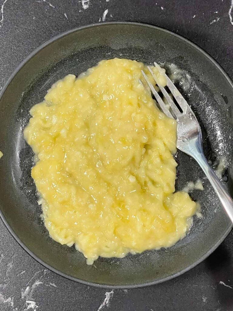 Mashed ripe banana in a bowl ready for banana pancake batter.