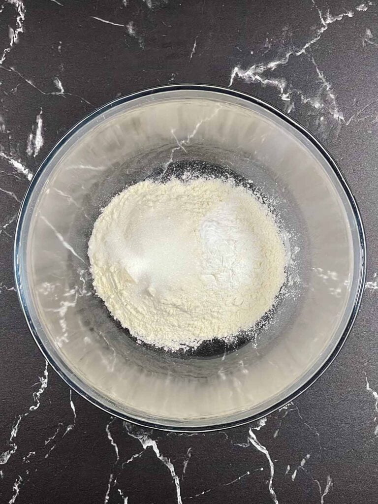 Flour, baking powder, baking soda, and kosher salt in a mixing bowl for pancakes.