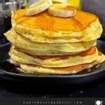 Fluffy banana pancakes stacked high with golden edges and soft centers, served with syrup.