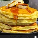 Fluffy banana pancakes stacked high with golden edges and soft centers, served with syrup.