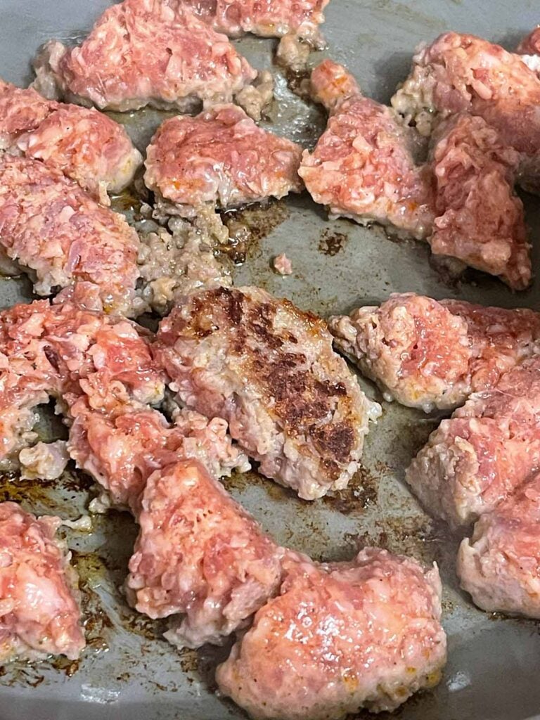 Breakfast sausage cooking in a skillet.