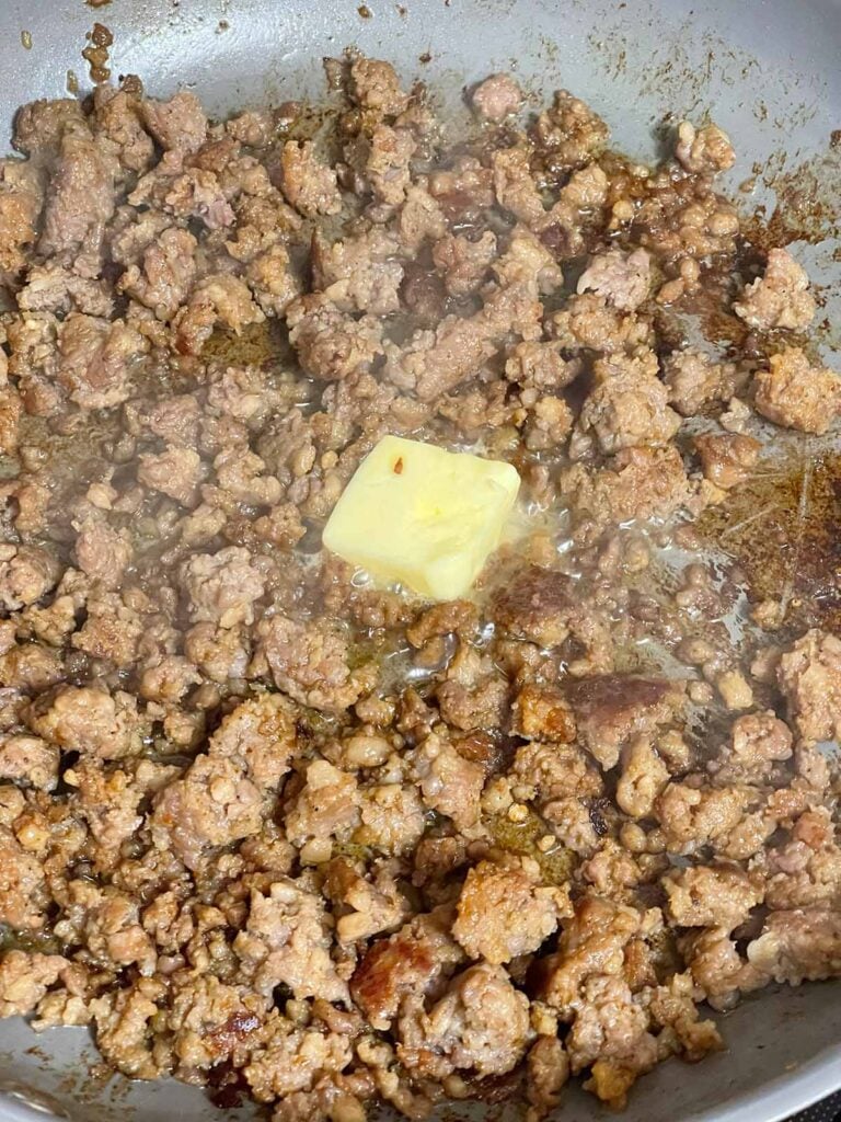 A pat of butter melting in cooked sausage.
