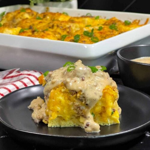 A serving of biscuits and gravy breakfast casserole on a dark plate.
