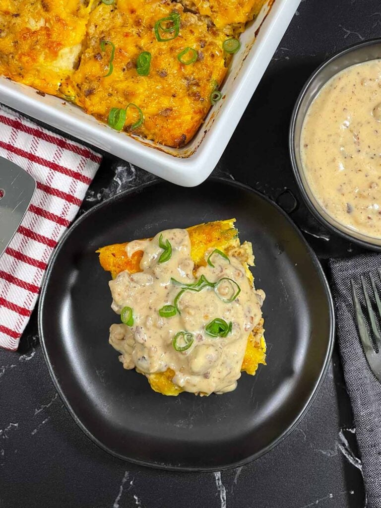 A serving of biscuits and gravy breakfast casserole on a dark plate.
