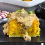 A serving of biscuits and gravy breakfast casserole on a dark plate.