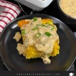A serving of biscuits and gravy breakfast casserole on a dark plate.