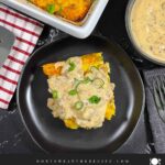 A serving of biscuits and gravy breakfast casserole on a dark plate.