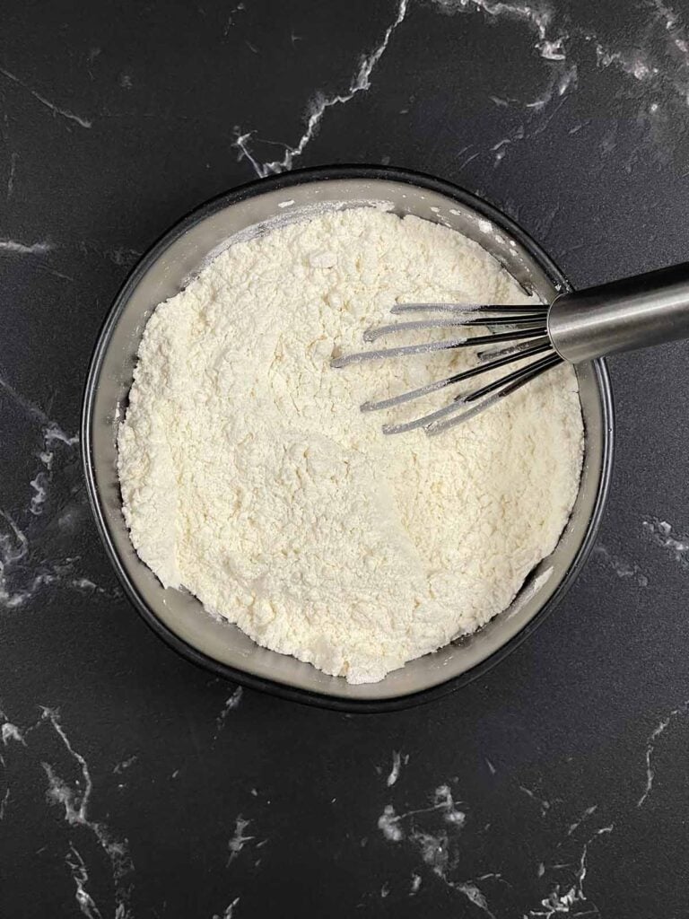 A bowl of flour in a dark bowl.