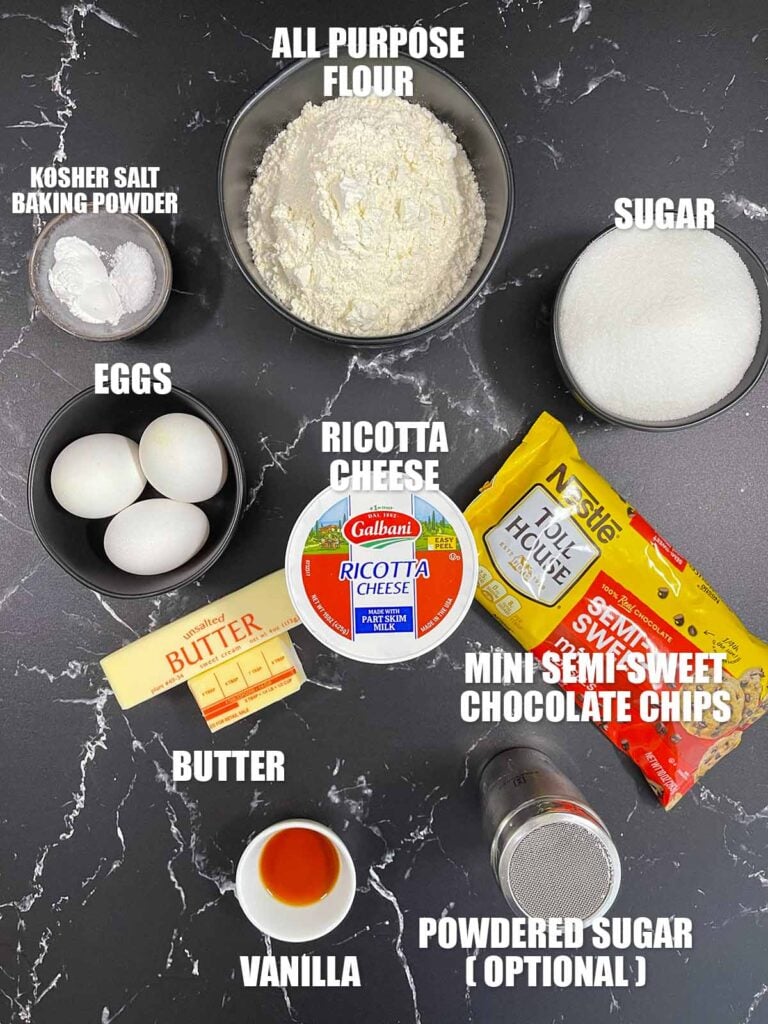 Chocolate chip ricotta cake recipe ingredients on a dark surface.