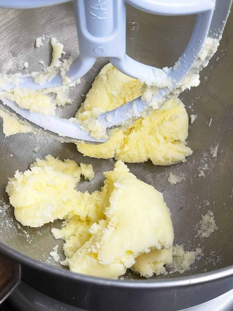 Butter and sugar creamed together in a metal mixing bowl.