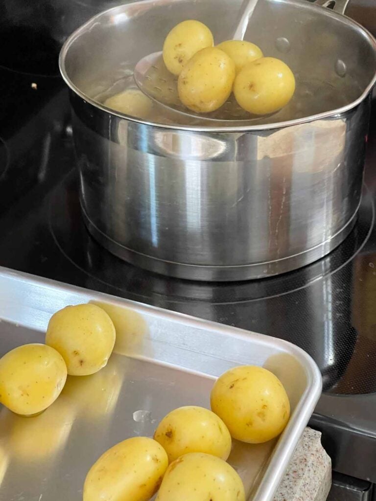 Transferring drained baby potatoes to a sheet pan.