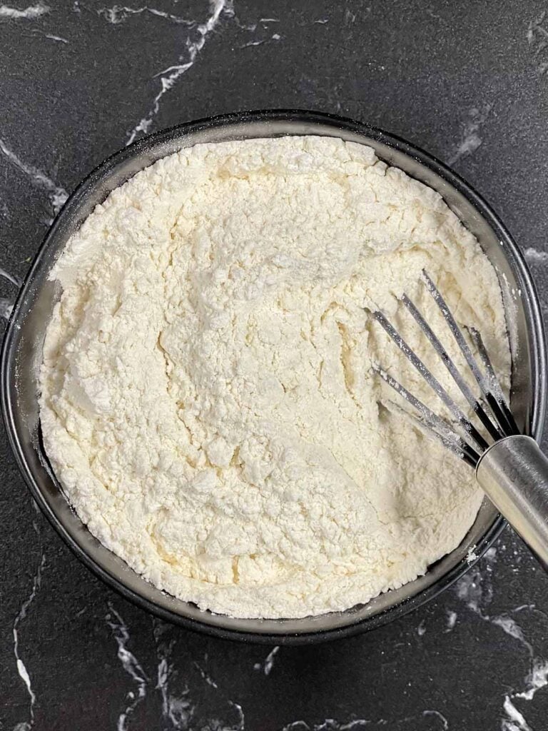 Dry ingredients for lemon crumb muffins whisked together in a dark bowl.