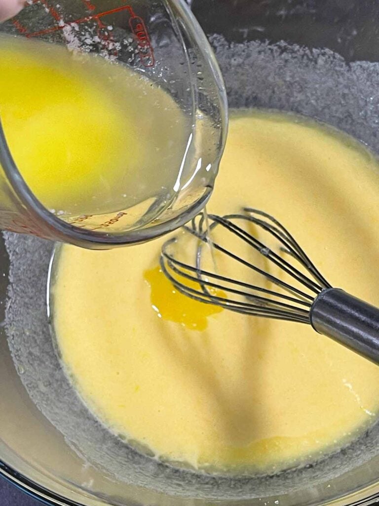 Melted and cooled butter being slowly added to the wet ingredients.
