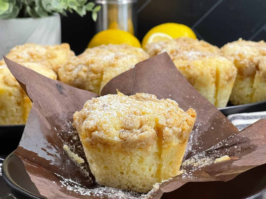 Freshly baked lemon crumb muffins with golden domed tops and crisp streusel topping.