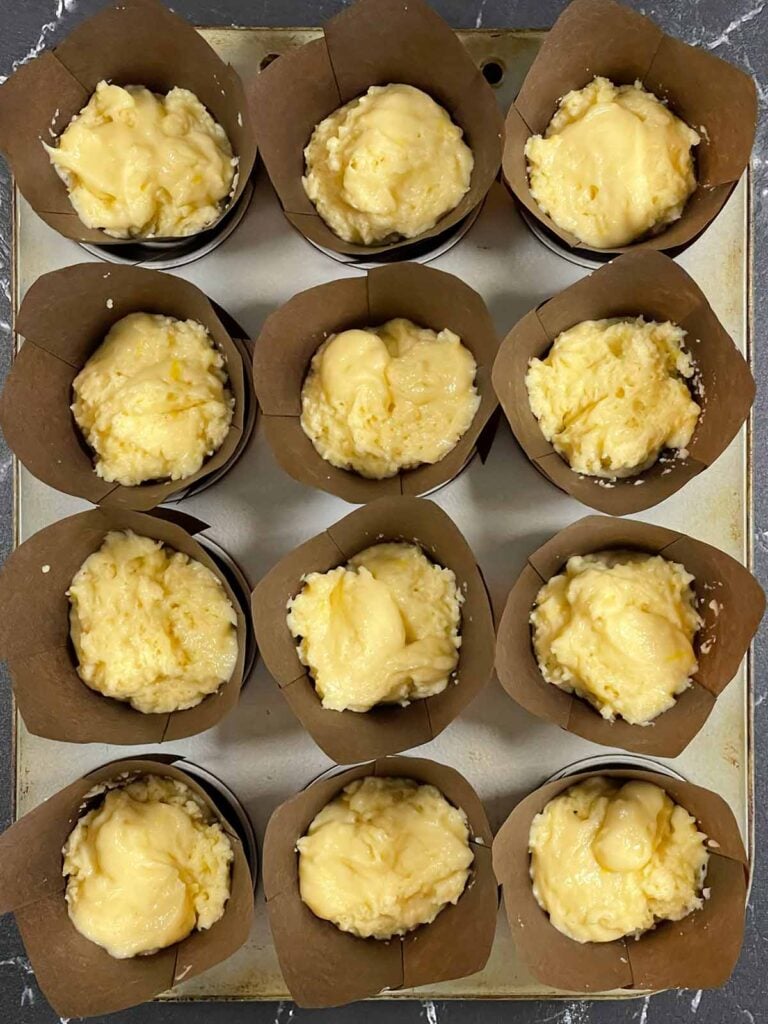 Unbaked lemon crumb muffins topped with crumbly streusel before going into the oven.