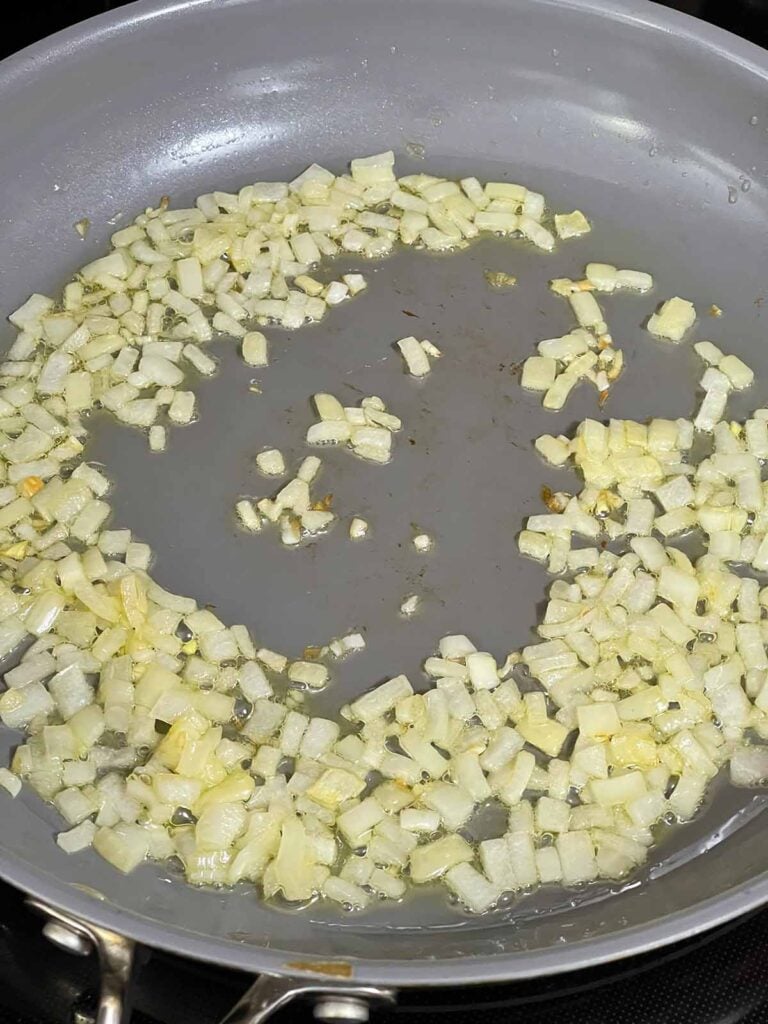 Onions becoming translucent in a skillet.