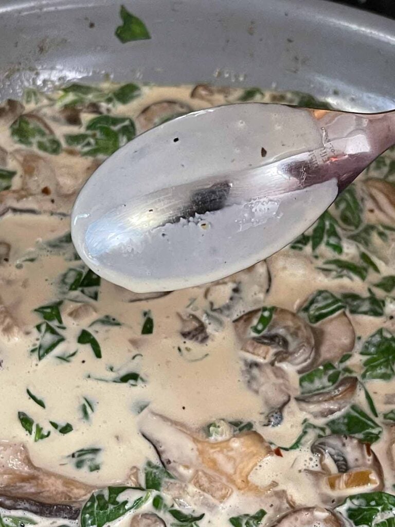 Testing a cream sauce by wiping a finger across the back of a spoon.