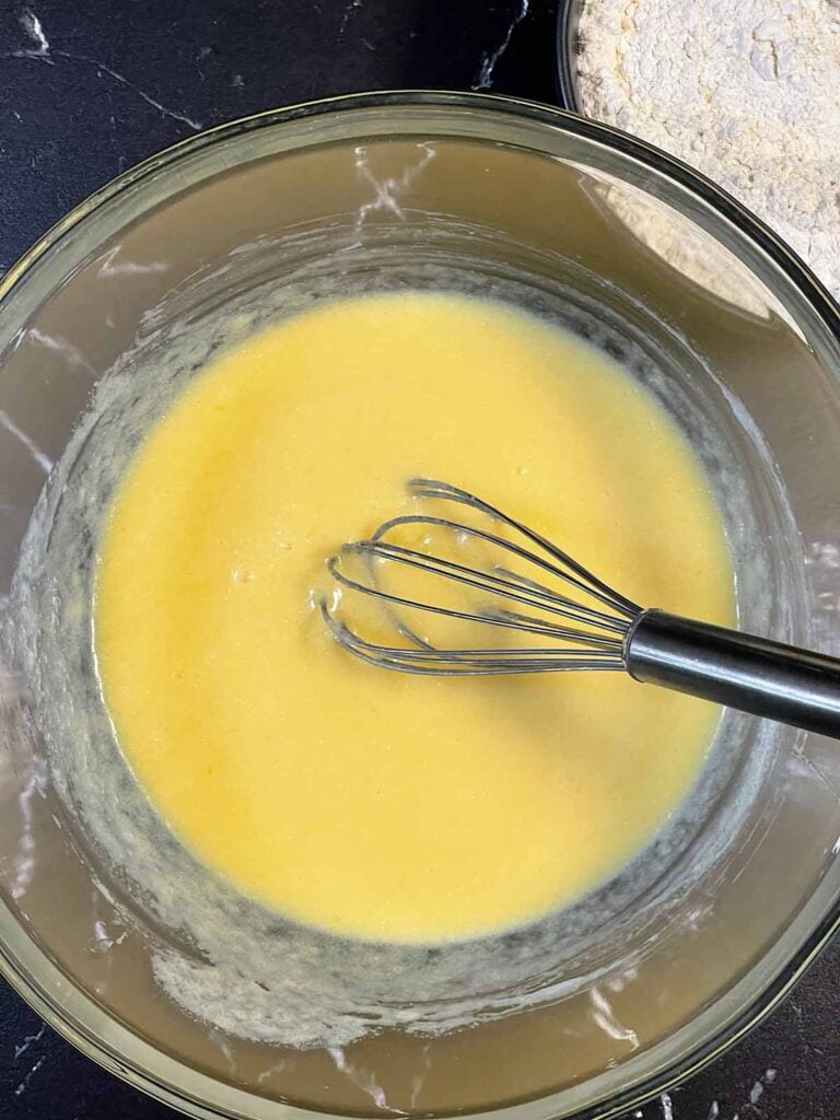 Wet ingredients including milk, eggs, melted butter, and vanilla mixed in a separate bowl.