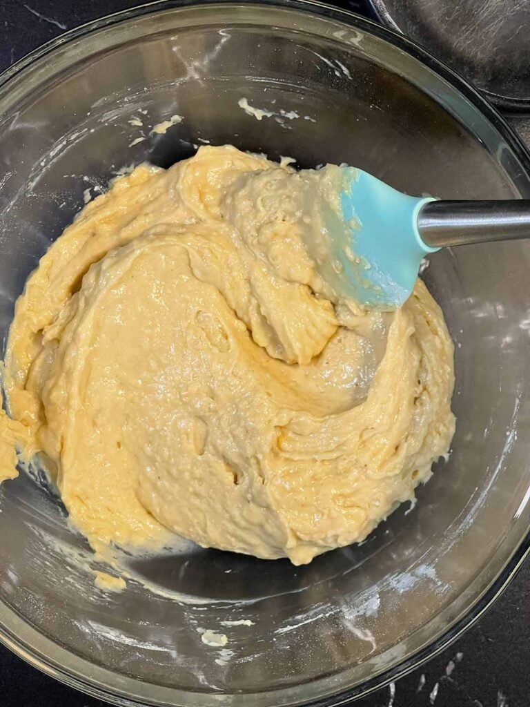 Donut batter being mixed until just combined in a bowl.