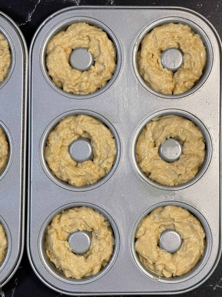 Donut batter spooned into a greased donut pan.