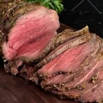 Sliced beef sirloin tip roast cooked medium rare on a wooden cutting board