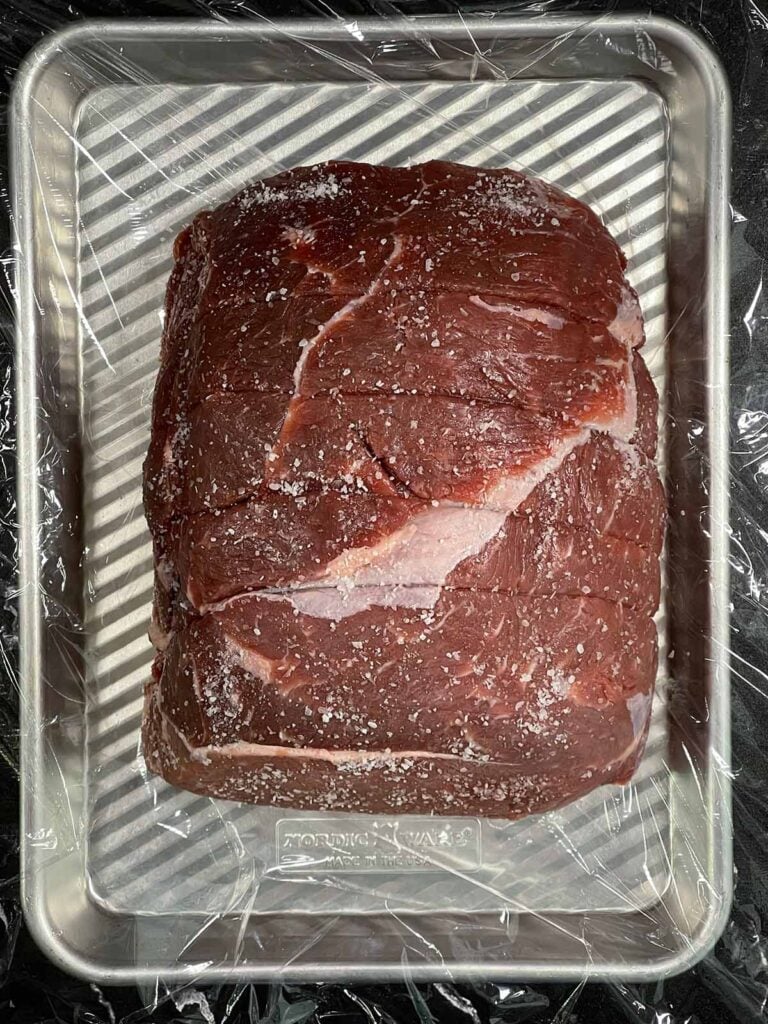Sirloin tip roast, seasoned, on a baking sheet.