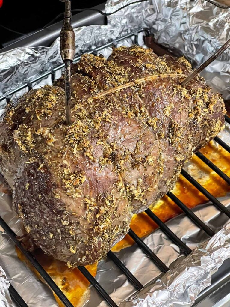 Beef sirloin tip roast being checked with a meat thermometer while roasting