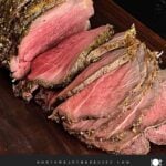 Sliced beef sirloin tip roast cooked medium rare on a wooden cutting board