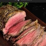 Sliced beef sirloin tip roast cooked medium rare on a wooden cutting board