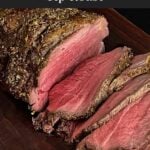 Sliced beef sirloin tip roast cooked medium rare on a wooden cutting board
