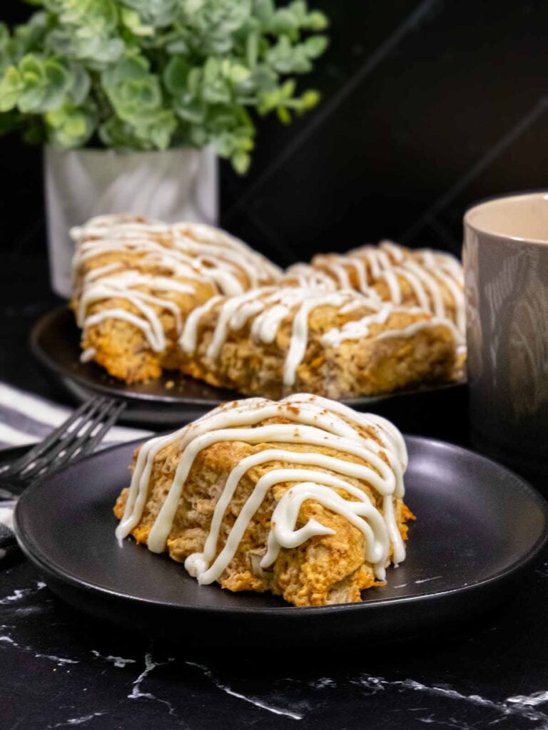 Carrot cake scone on a dark plate garnished with ground nutmeg and cinnamon.