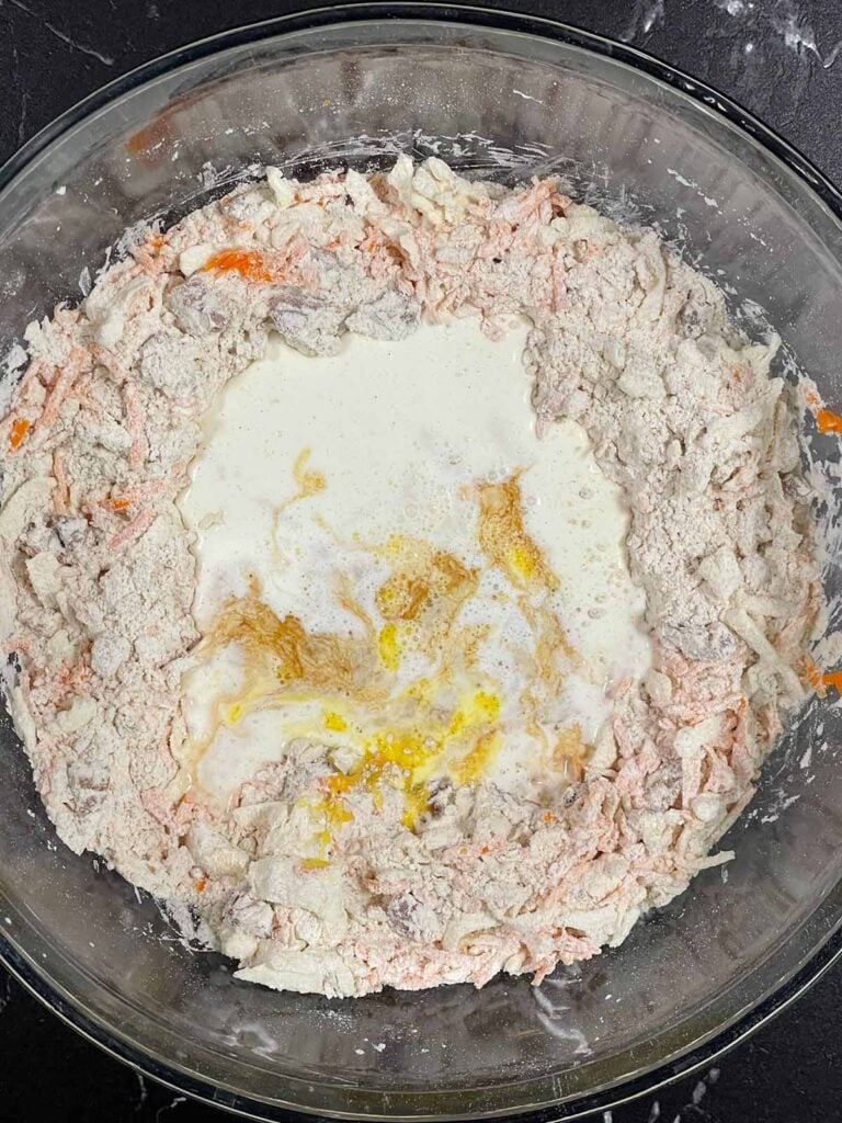 Wet ingredients added to a well in the center of the dry ingredients for carrot cake scones recipe.