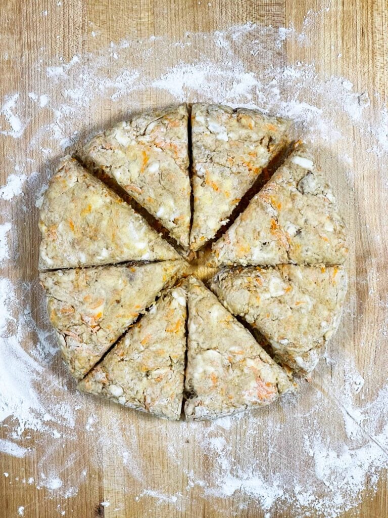 Scone dough cut into eight triangles on a wooden surface.
