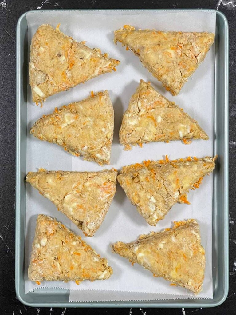 Raw scones placed on a parchment paper lined baking sheet.