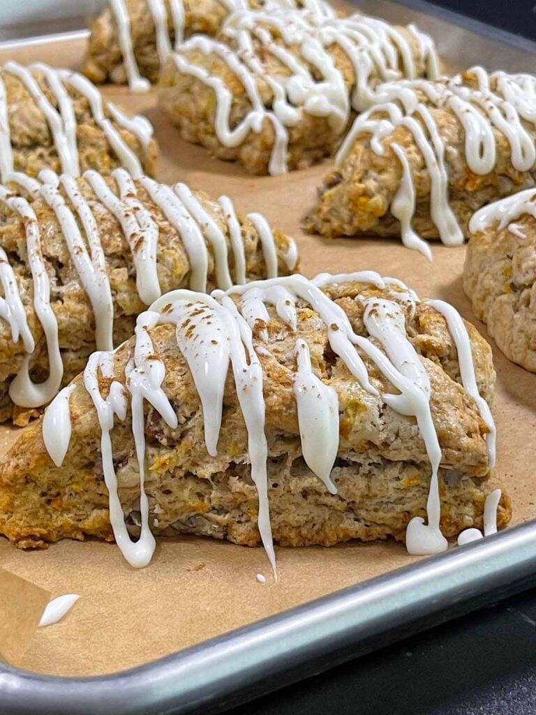 Carrot cake scones on a parchment paper lined baking sheet.